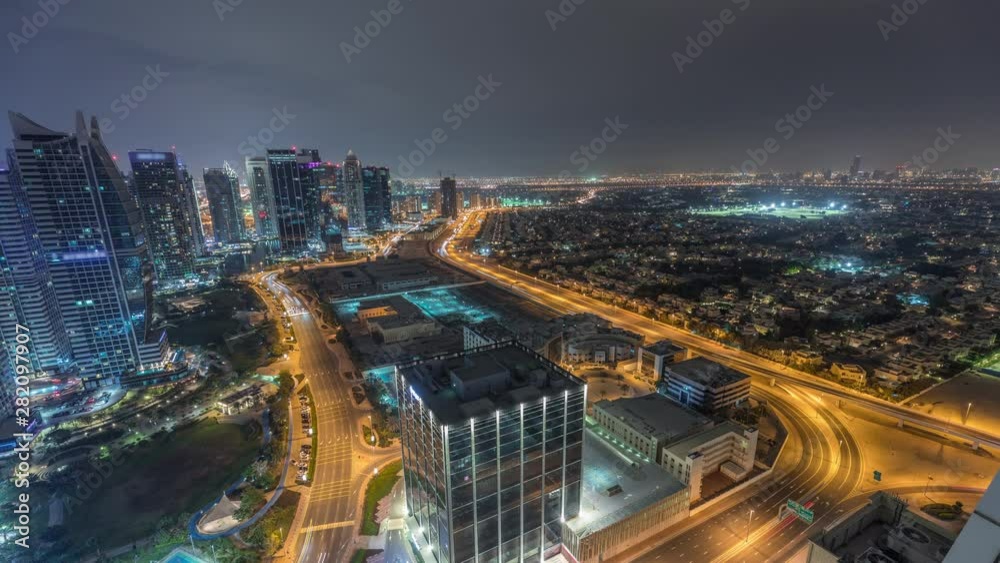 Jumeirah Lake Towers residential district aerial night timelapse near Dubai Marina. Illuminated modern skyscrapers and traffic from above. Villas and houses on a background Jumeirah Lake Towers residential district aerial night timelapse near Dubai Marina. Illuminated modern skyscrapers and traffic from above. Villas and houses on a background
