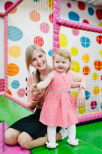 Mother and daughter, happy family playing and jumping on trampoline in childrens playroom, sport centre indoors playground on birthday party. Celebration concept holiday, entertainment.
