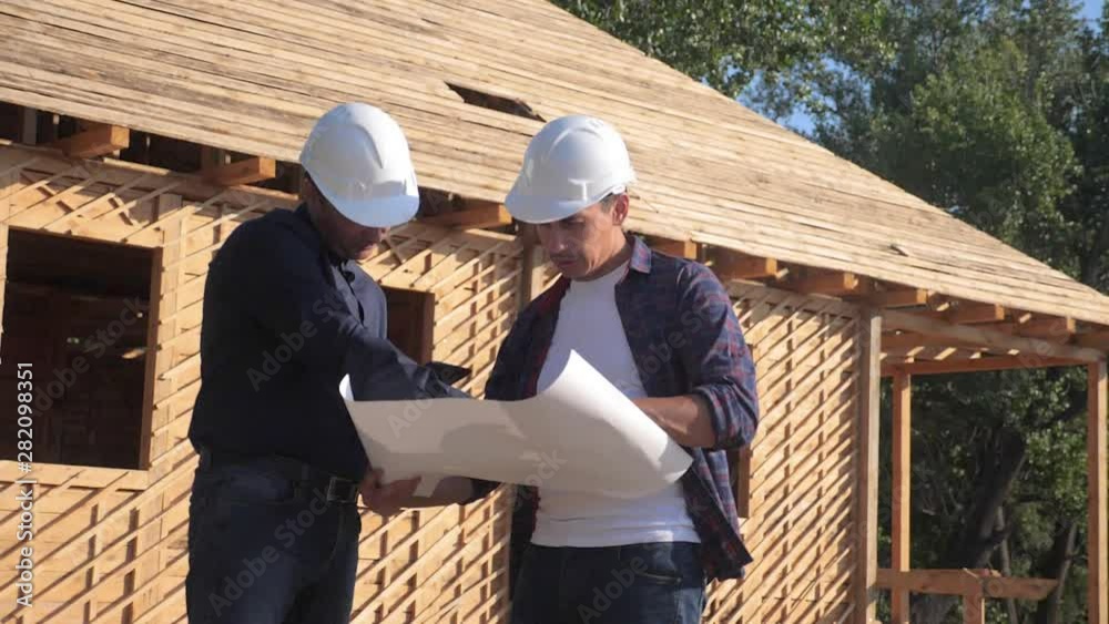 teamwork. concept building constructing architect slow motion video. two men builder in helmets study the house plan. two architects working lifestyle on the construction of a frame house business teamwork. concept building constructing architect slow motion video. two men builder in helmets study the house plan. two architects working lifestyle on the construction of a frame house business