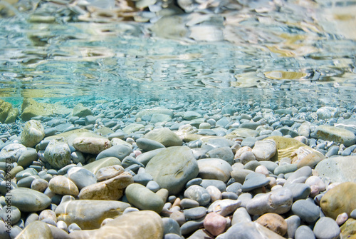 Sea stones in the sea water and ripples. Pebbles under water. Nautical background. Clean sea water. Transparent sea. Mediterranean sea.