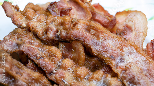 Cooked, appetizing bacon rashers on plate, closeup