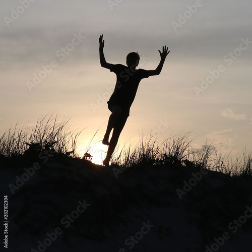 Silhouette Jumping off Sand Dune at Sunset