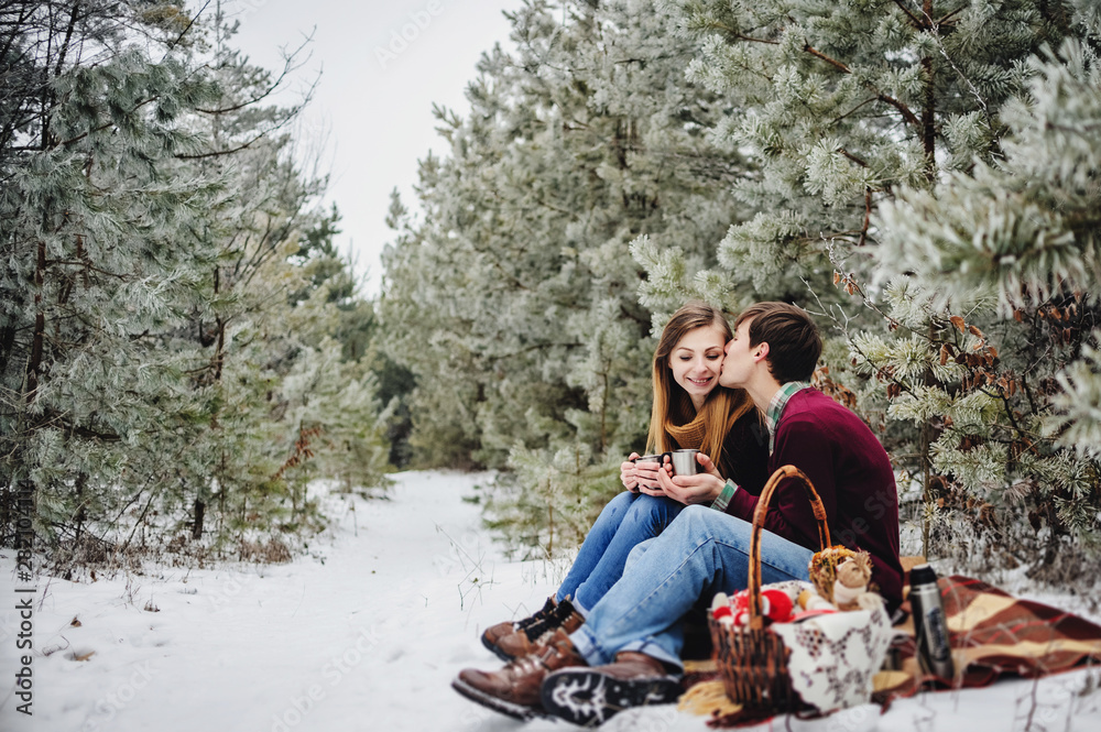 People, season, love and leisure concept - happy young couple hugging and laughing outdoors in winter. Man and woman walk in snow park.