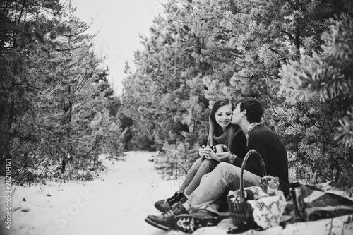 A romantic love couple walks in the snow park. Happy winter holidays. Black and white photo.
