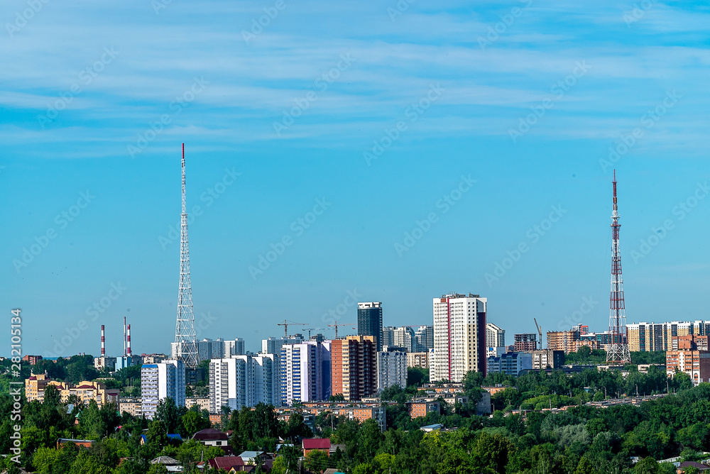 Before us is the area of the City Hills of Perm. On the hill there are high-rise and one-storey houses, television towers, many trees. Summer, June, early morning.
