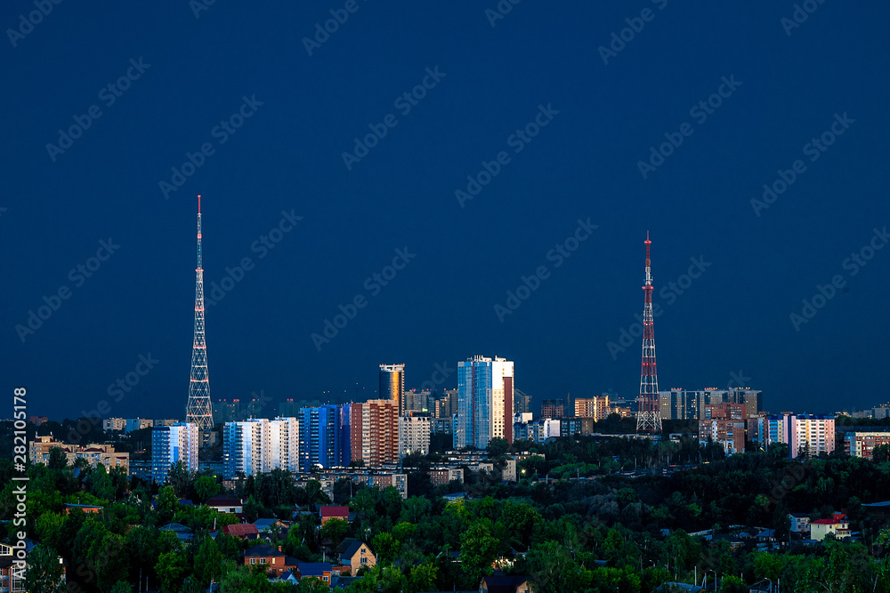Fototapeta premium In the rays of the sun setting close-up one of the Central regions of Perm. High-rise buildings and TV towers are illuminated by the last rays of the sun. Summer, July.