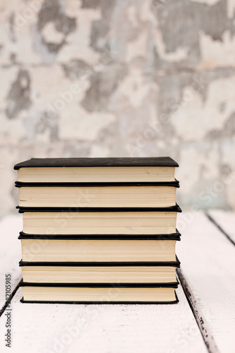 Stack of old ancient shabby books on a white wooden background.
