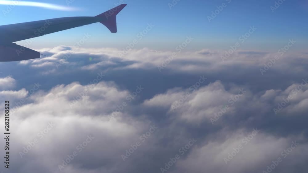Up in the air, view of aircraft wing silhouette with dark blue sky horizon and cloud background in sun rise time, viewed from airplane window Up in the air, view of aircraft wing silhouette with dark blue sky horizon and cloud background in sun rise time, viewed from airplane window