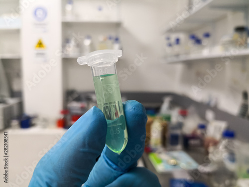 Representation of a scientist researching in a medical and chemical laboratory. A green liquid inside a vial with the concepts of research, laboratory, chemistry and biomedical research