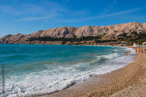  people resting on the beach on the famous beach in Baska