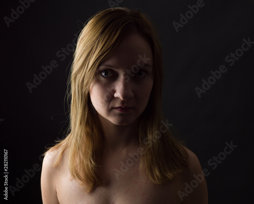 portrait of young woman, no make up, low key, brown dark hair, natural looking making expressions 