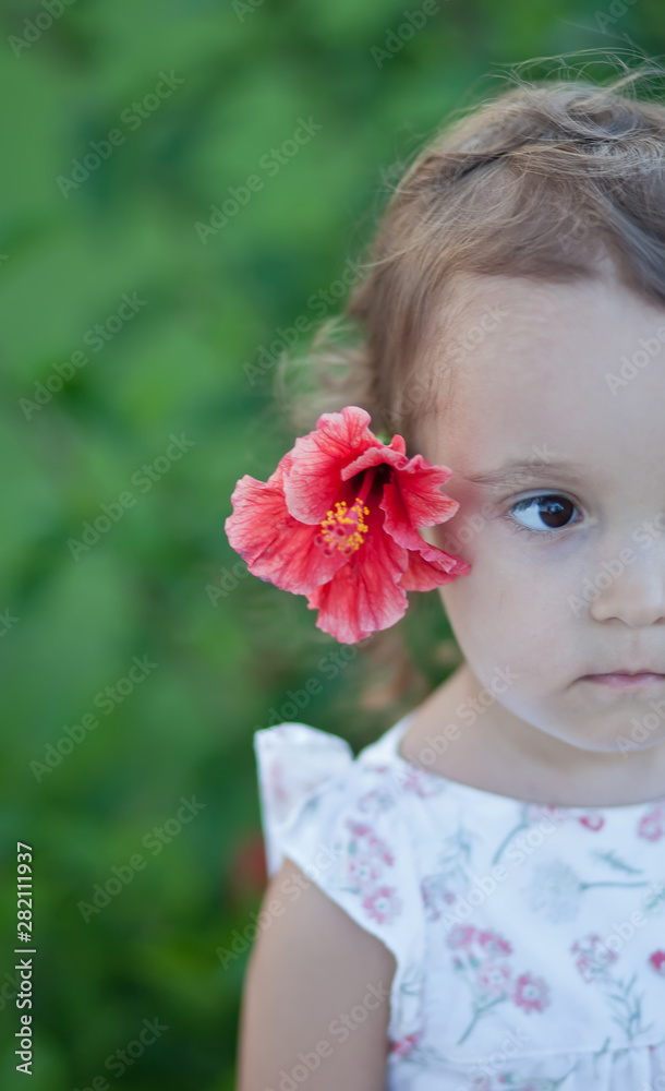 Little child girl with red flower behind her ear Little child girl with red flower behind her ear