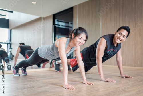 Asian couple doing push up together in fitness gym