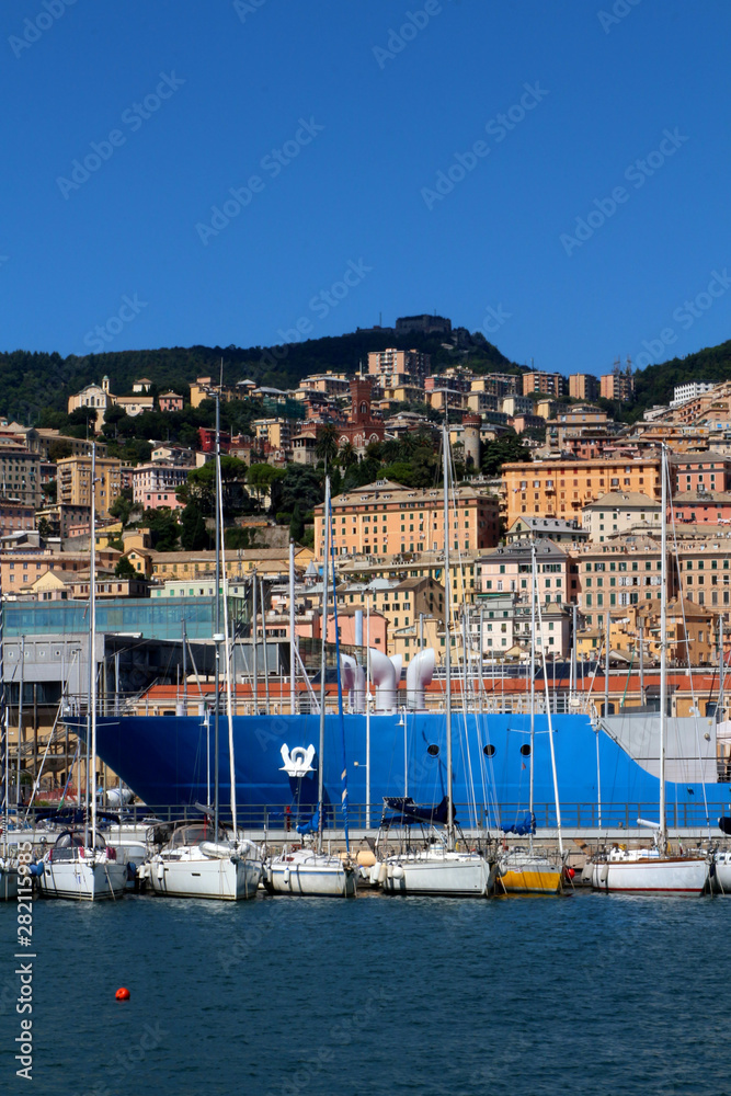 Sailing boats in front of the cityscape of Genoa, Italy