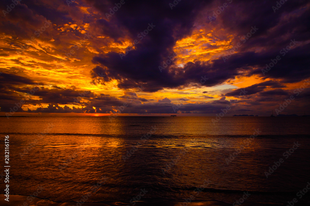 Burning sky and sea during sunset on tropical island after rain and storm with mystic reflection in the sea - Ko Lanta, Thailand