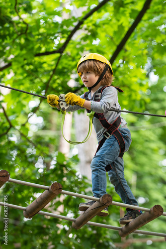 Child concept. Rope park - climbing center. Hike and kids concept. Go Ape Adventure. Happy Little child climbing a tree.
