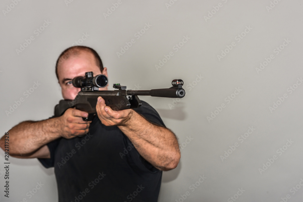 A boy with an air rifle looks into an optical sight. A boy with an air rifle looks into an optical sight.