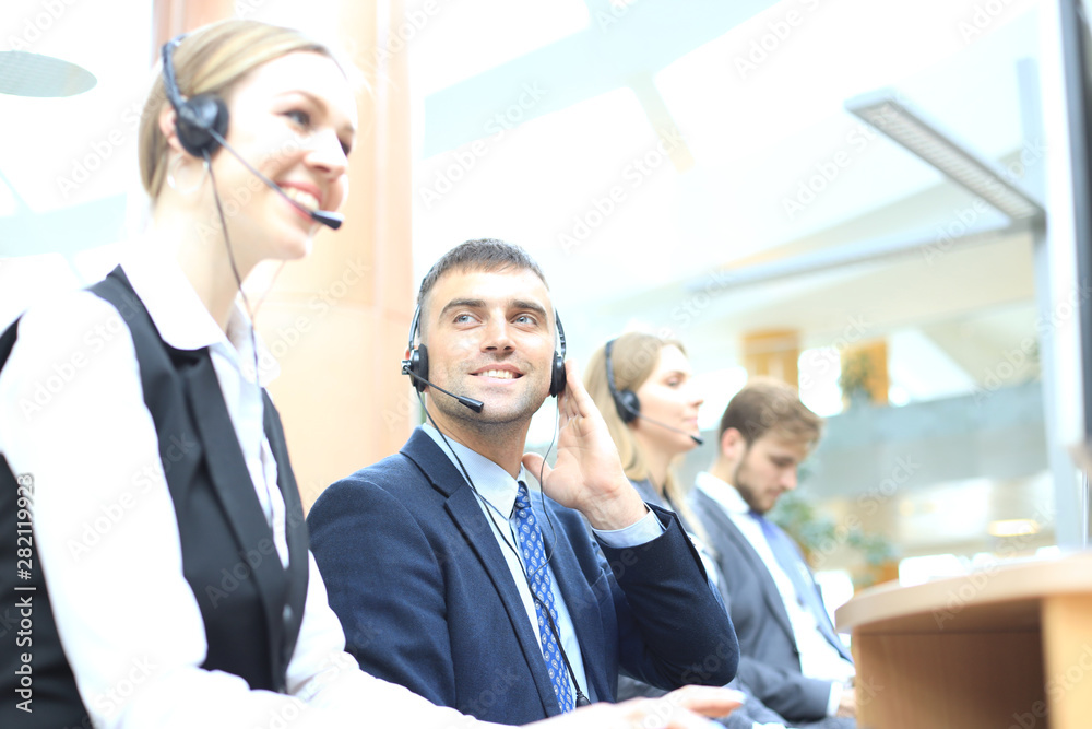 Portrait of call center worker accompanied by his team. Smiling customer support operator at work. Portrait of call center worker accompanied by his team. Smiling customer support operator at work.
