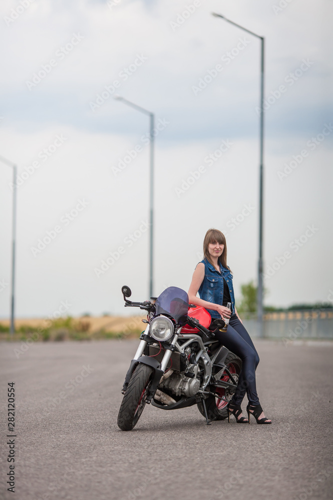 sexy biker woman sitting on a vintage custom motorcycle. Girl biker with perfect fit slim body. The spirit of freedom and independence. Beautiful brave woman is leaning on her motobike  on highway