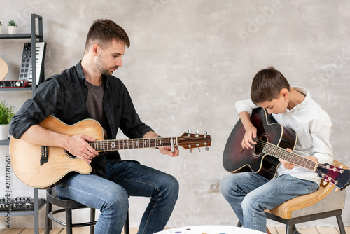 Wallpaper Mural Two brothers learn to play acoustic guitar. The older brother tunes the guitar while the younger one runs his finger along the strings Torontodigital.ca