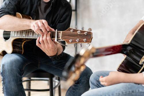 Wallpaper Mural Young man in black shirt teaches his younger brother to play guitar chords correctly Torontodigital.ca