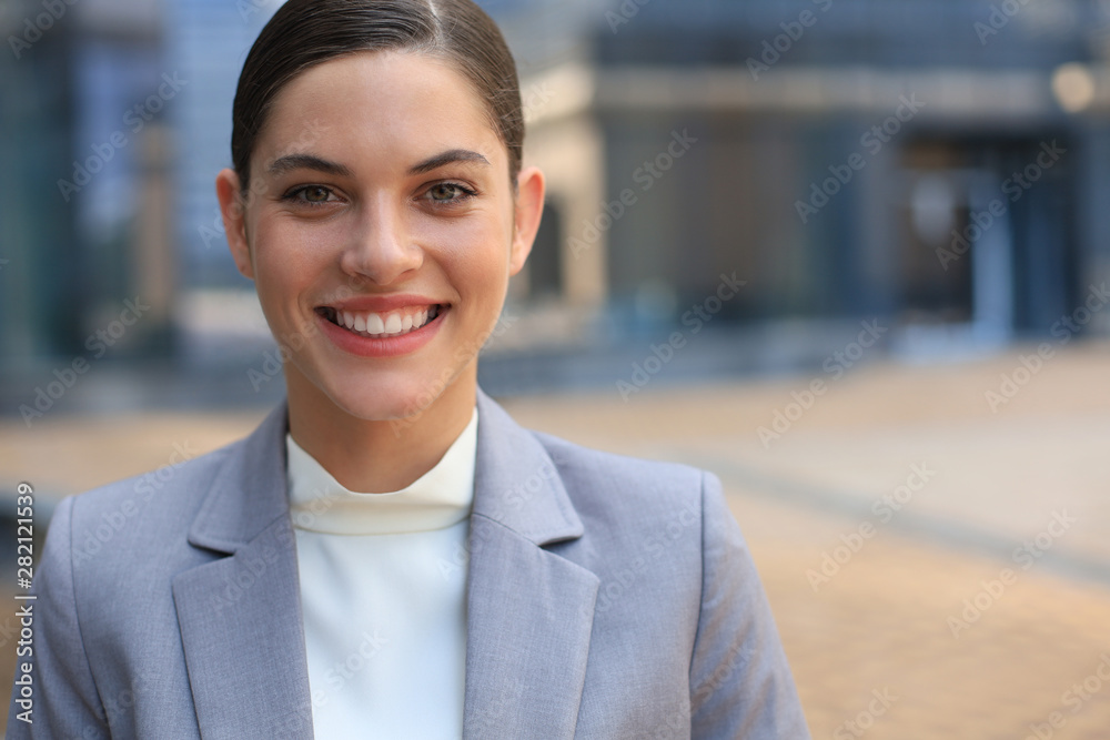 Attractive young woman in suit looking at camera and smiling while standing outdoors. Attractive young woman in suit looking at camera and smiling while standing outdoors.