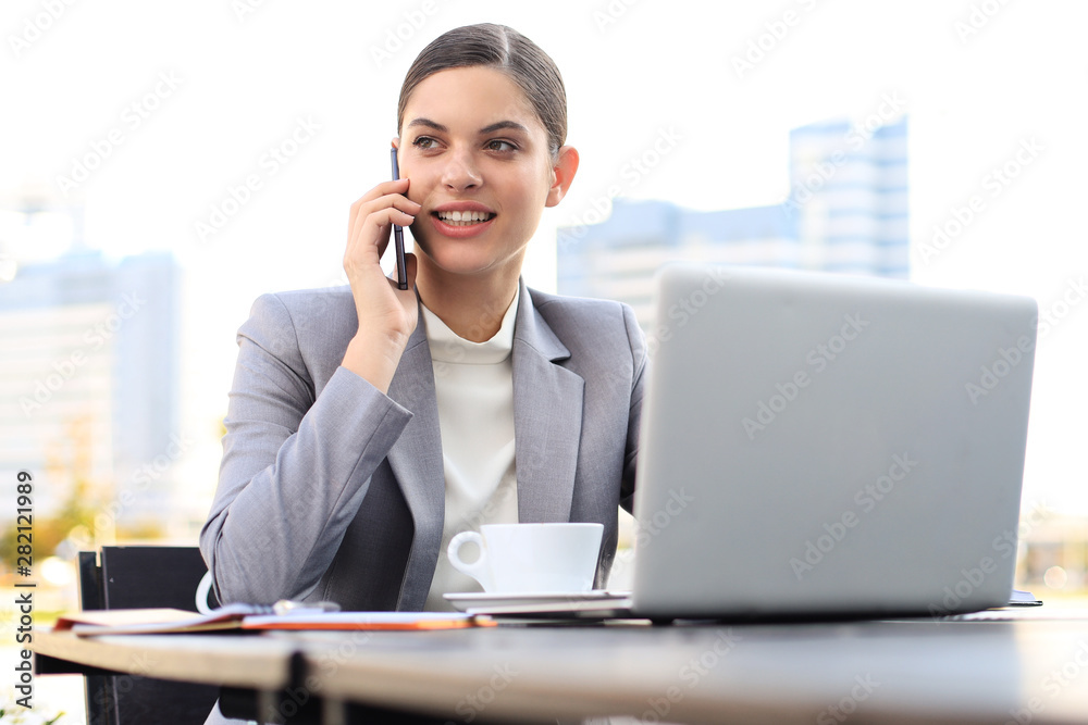 Portrait of successful business woman talking on the phone and smiling while working in the modern cafe. Portrait of successful business woman talking on the phone and smiling while working in the modern cafe.