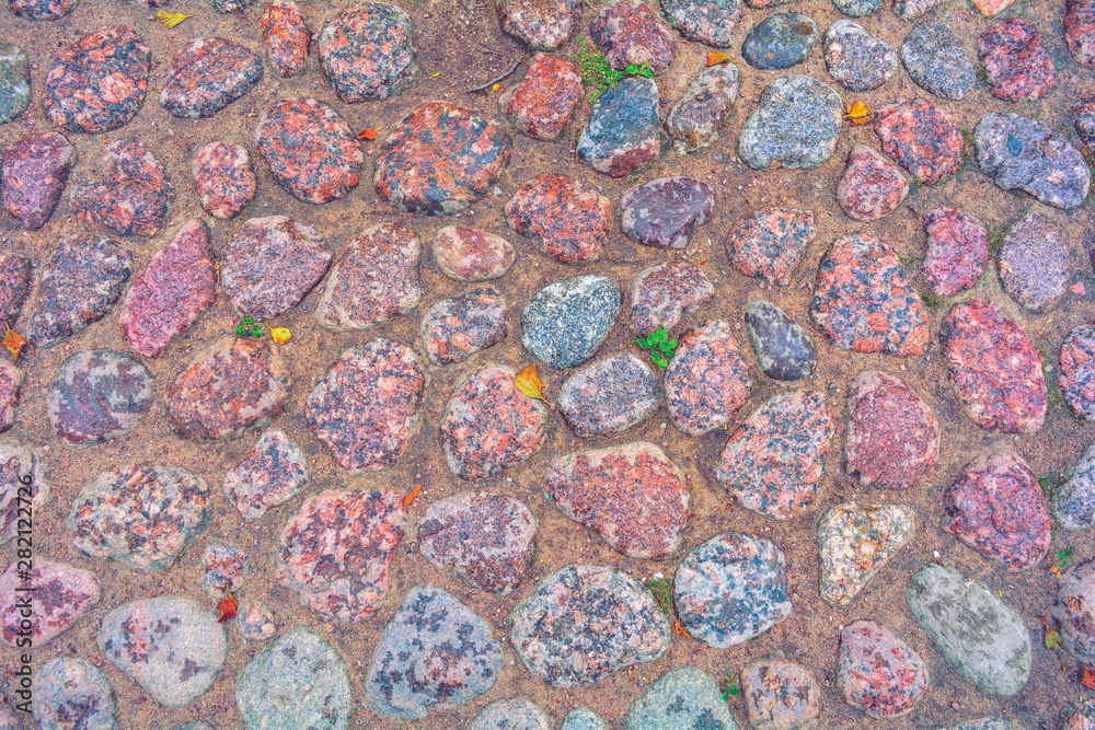 Stone pavement with rough wet granite boulders. Historic medieval cobble paving