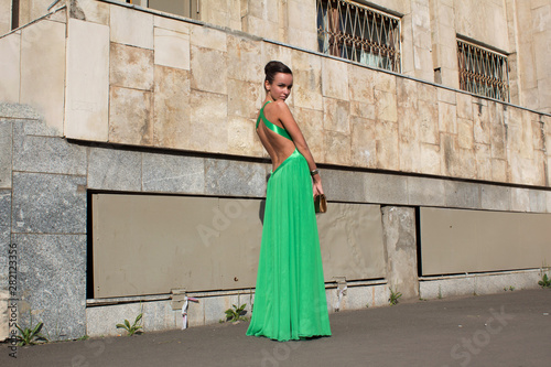 elegant woman in green dress posing against a concrete wall © Сергей Курбатов
