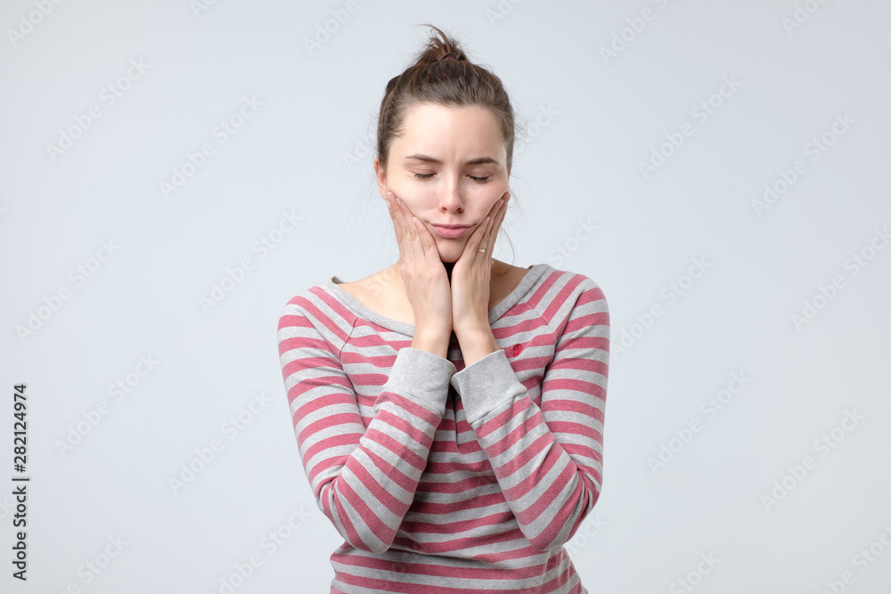 Teenage girl holding hands on her cheeks, being sad that they are too big. Studio shot Teenage girl holding hands on her cheeks, being sad that they are too big. Studio shot