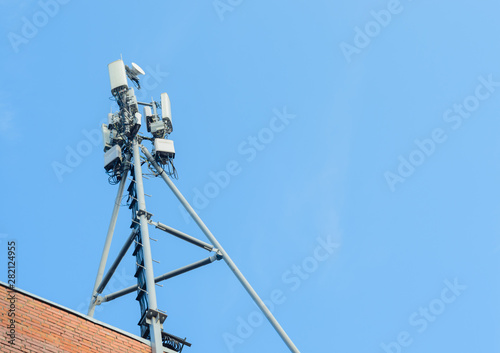 Cellular antenna on the roof of a brick house on blue sky background,copyspace.