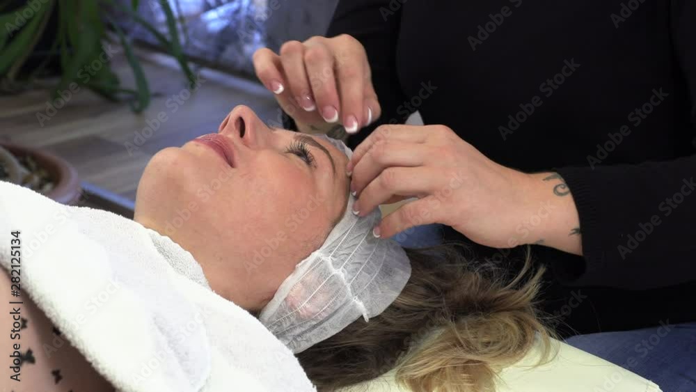 Beautician makes brunette microblading procedures in a cosmetic studio Beautician makes brunette microblading procedures in a cosmetic studio