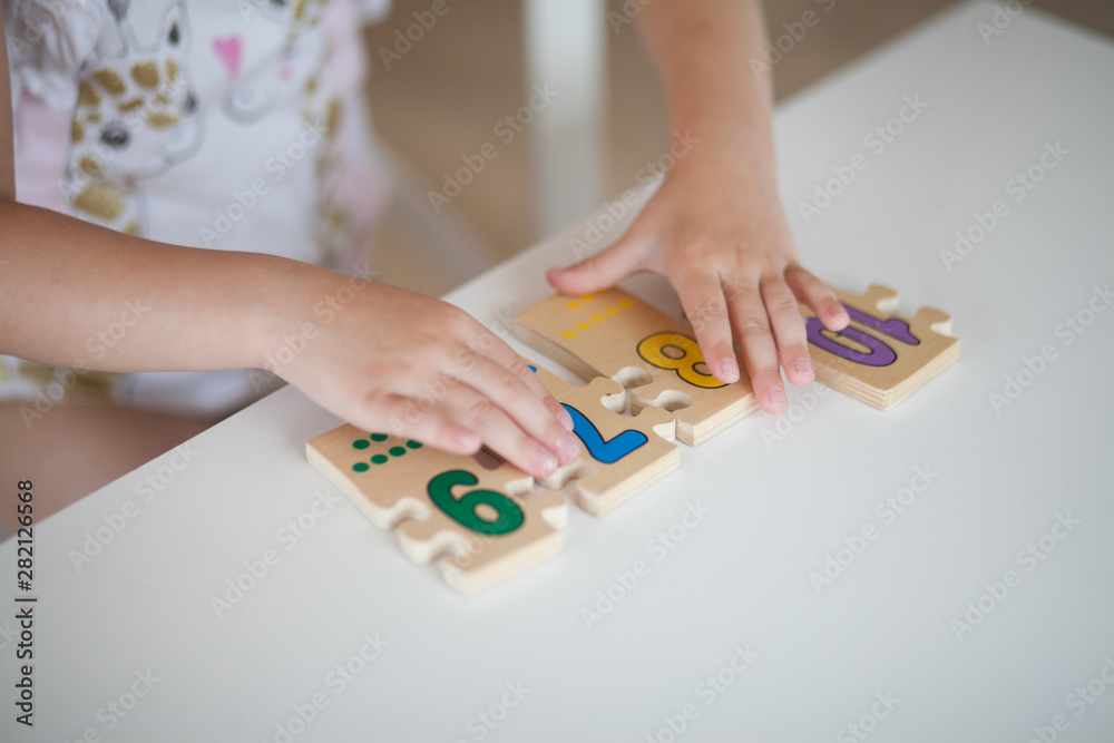 Close up hands of little girl playing with figures while sitting at table 