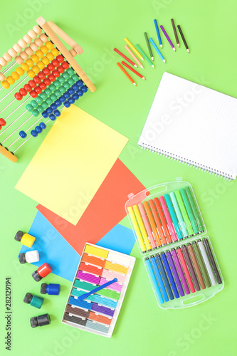 Assorted office or school sets of multicolored rainbow stationery on pastel green background. Flat lay with copy space. back to school or creative education craft design concept.