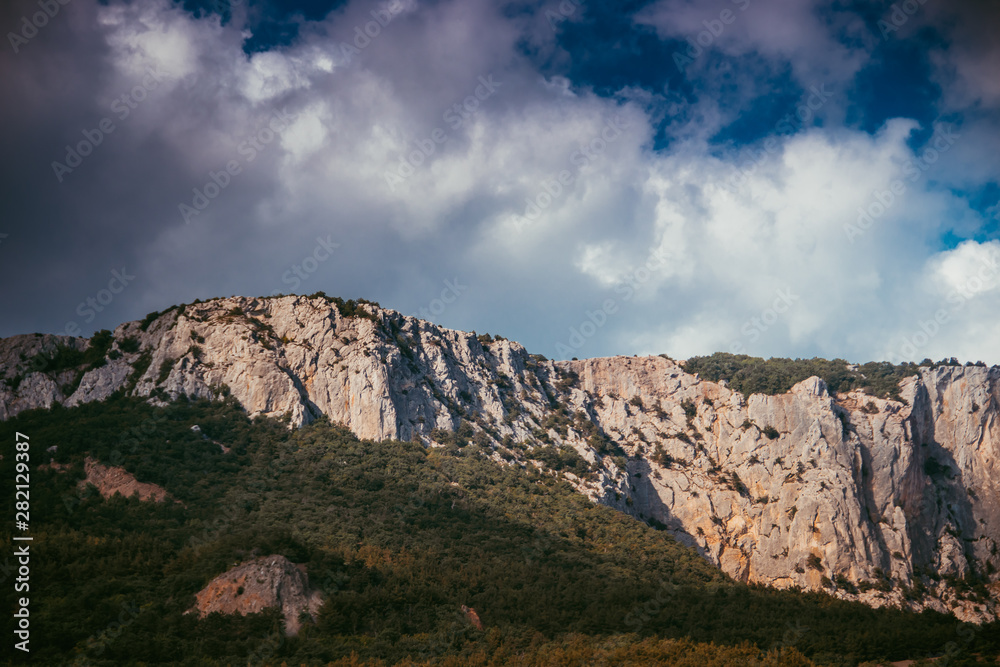 Russian mountains. Crimea. Summer mountains background. Forest and mountains in the sun on the background of a cloudy sky above the peninsula of Crimea. Sunny, bright, saturated raster photo