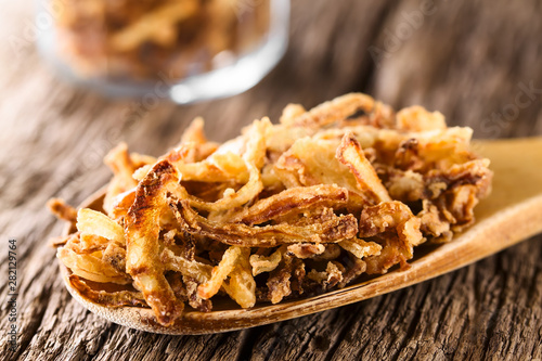 Fotografie Fresh homemade crispy fried onion strings on wooden spoon (Selective Focus, Focu