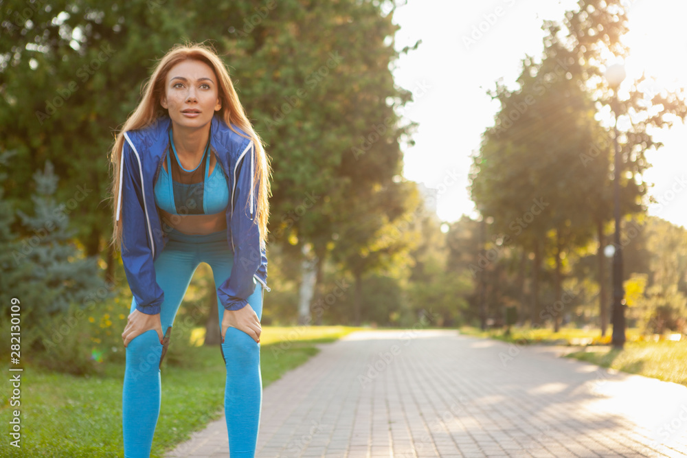 Beautiful sportswoman resting after jogging in the park, copy space. Attractive athletic female relaxing after running outdoors. Female jogger working out in the morning Beautiful sportswoman resting after jogging in the park, copy space. Attractive athletic female relaxing after running outdoors. Female jogger working out in the morning