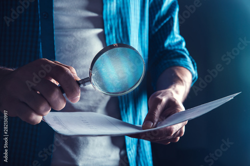 man hand document with magnifier on dark background