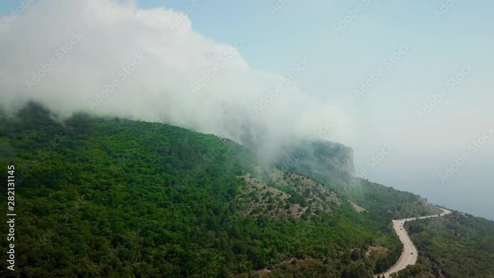 Dorne point of view of clouds fly under mountains and highway road between the mountains. Dorne point of view of clouds fly under mountains and highway road between the mountains.