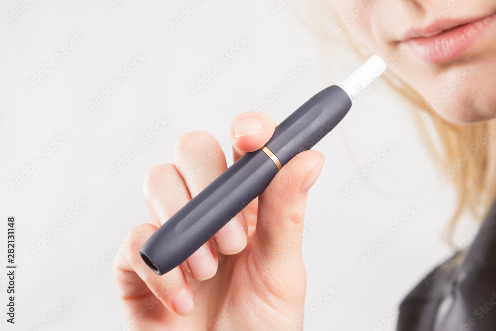 Blond girl offering tobacco heating system device with tobacco stick. Blond girl offering tobacco heating system device with tobacco stick.