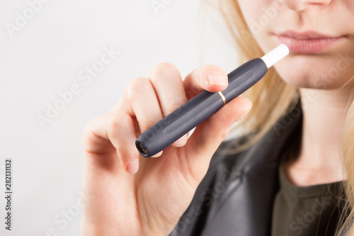 Blonde women holding tobacco heating system device with tobacco stick