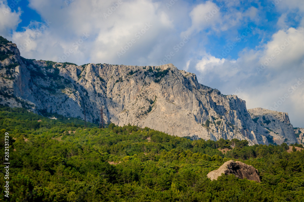 Russian mountains. Crimea. Summer mountains background. Forest and mountains in the sun on the background of a cloudy sky above the peninsula of Crimea. Sunny, bright, saturated raster photo