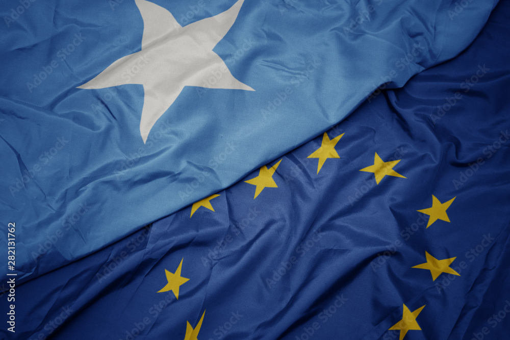 waving colorful flag of european union and flag of somalia. waving colorful flag of european union and flag of somalia.