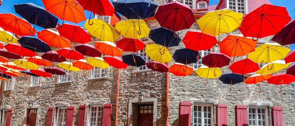 Naklejka premium Kolorowe parasole zawieszone nad ulicą w Quebec City