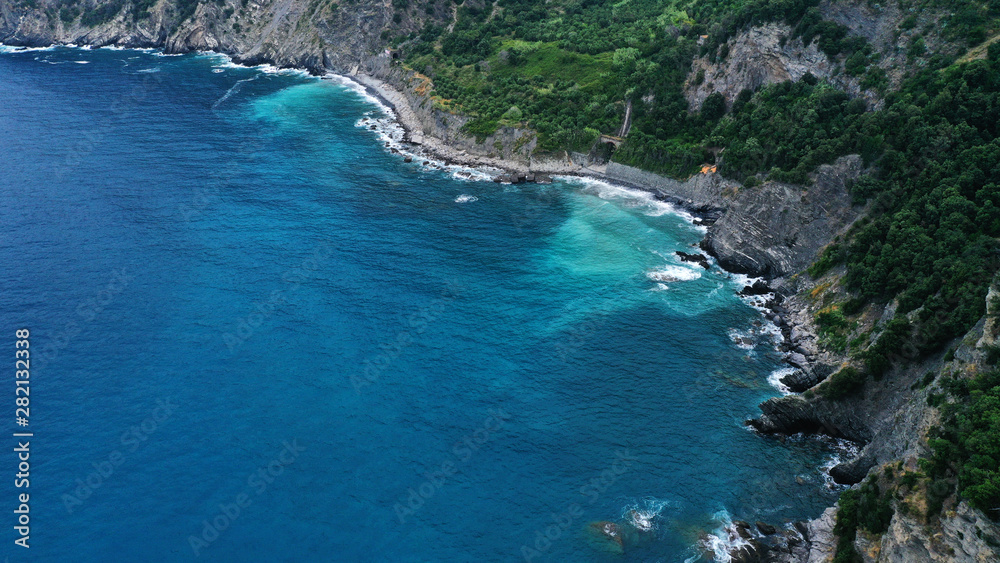 Aerial view of rocky coast and blue sea with white foaming waves.
