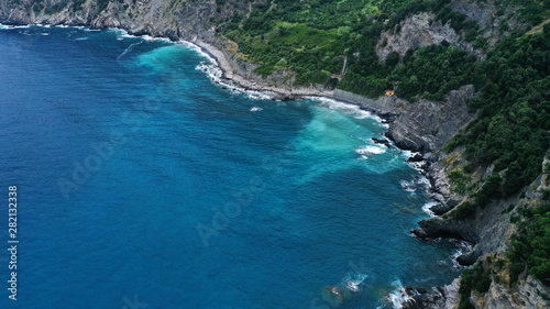Aerial view of rocky coast and blue sea with white foaming waves.