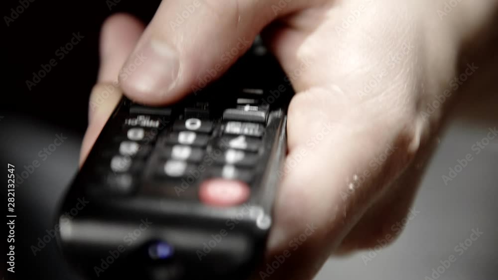 Caucasian hand changing the volume on a TV remote. Caucasian hand changing the volume on a TV remote.