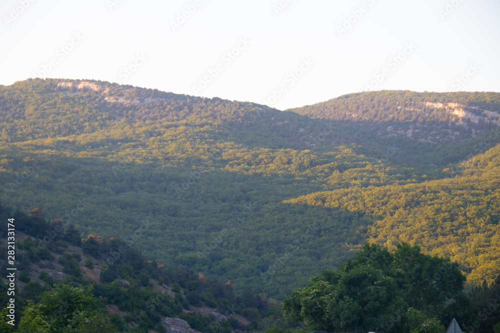 Russian mountains. Crimea. Summer mountains background. Forest and mountains in the sun on the background of a cloudy sky above the peninsula of Crimea. Sunny, bright, saturated raster photo Russian mountains. Crimea. Summer mountains background. Forest and mountains in the sun on the background of a cloudy sky above the peninsula of Crimea. Sunny, bright, saturated raster photo