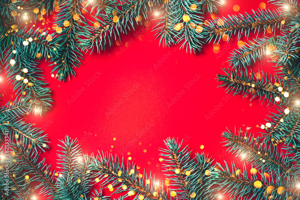 Fir branches with blurred lights garland on a red background. Christmas wallpaper. Flat lay, copy space. Fir branches with blurred lights garland on a red background. Christmas wallpaper. Flat lay, copy space.