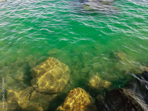 Large stones under the water of the sea with small crabs on a summer sunny day.